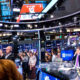 Tampilan layar perdagangan saham di Wall Street dengan grafik indeks yang fluktuatif