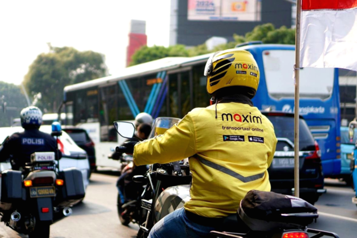 Pengemudi ojek daring Maxim sedang menunggu penumpang di pinggir jalan Jakarta.