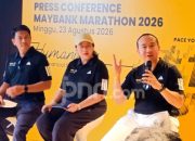Pelari mengikuti ajang Maybank Marathon di jalanan Bali dengan latar belakang pemandangan khas daerah Gianyar.