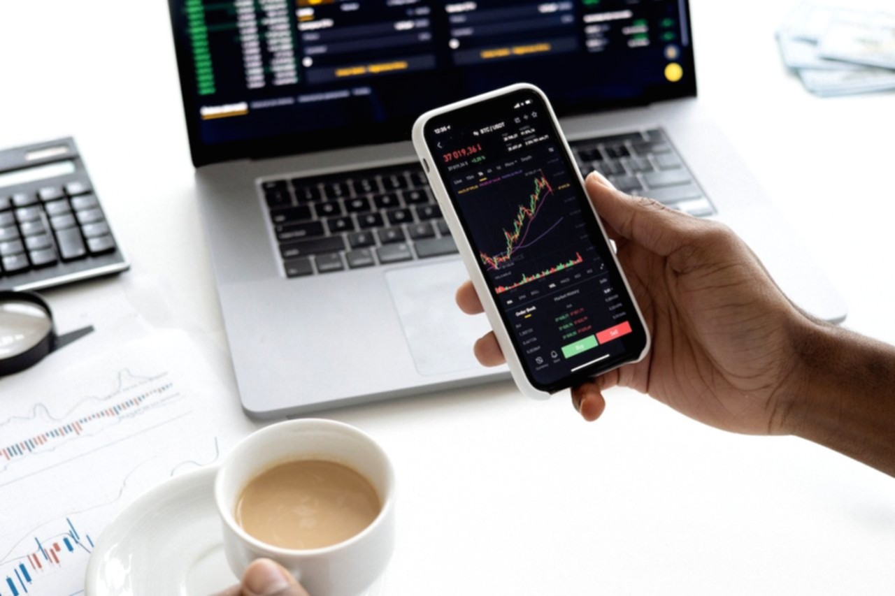 Seorang pengguna menggunakan aplikasi investasi saham di ponsel pintar untuk memantau portofolio keuangan