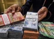 Papan layar elektronik menampilkan pergerakan nilai tukar mata uang rupiah terhadap dolar AS di Jakarta.